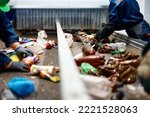 Small photo of Worker sorts trash on conveyor belt at waste recycling plant