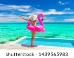 Vacation woman in bikini with inflatable pink flamingo float pool toy mattress by swimming pool. Elegant lady relaxing sunbathing enjoying travel holidays at resort pool. Luxury lifestyle travel,