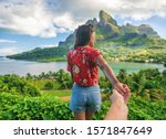 Small photo of Follow me couple influencers tourists walking on Bora Bora island, Tahiti. Woman leading man off the beaten path exploring nature hiking trail in French Polynesia. Mt Otemanu wanderlust summer travel.