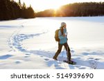 Winter sport activity. Woman hiker hiking with backpack and snowshoes snowshoeing on snow trail forest in Quebec, Canada at sunset. Beautiful landscape with coniferous trees and white snow.