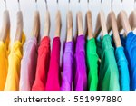 Fashion clothes on clothing rack - bright colorful closet. Closeup of rainbow color choice of trendy female wear on hangers in store closet or spring cleaning concept. Summer home wardrobe.