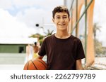 Small photo of Portrait of a boy with a basketball on a basketball court. The concept of a sports lifestyle, training, sport, leisure, vacation