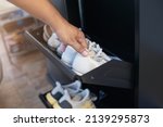 Man opening black steel shoes storage cabinet for keep her shoes. The man picks up shoes from black shoe storage