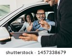 Small photo of Middle age couple choosing and buying car at car showroom. Car salesman helps them to make right decision.