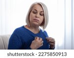 Small photo of A woman in an uncomfortable position due to the discomfort of menopausal hot flushes. Mature woman experiencing hot flush from menopause at home