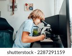 Small photo of Caucasian boy using a microscope at home at his study place. Child curiosity, thirst for knowledge, home learning experience, home remote education concepts. Selective focus.