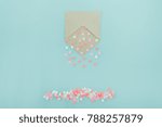 Small photo of Multicolor sweets sugar candy hearts pour forth of craft paper envelope on the light blue background . Valentine day. love concept. Gift, message for lover. Space for text. Selective focus