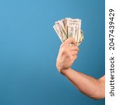 Small photo of Take my money, the willingness to pay for a cool product, a concept. A man's hand clutches a wad of cash, a photo on a blue background