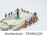 Small photo of Miniature figurine toys holding US twenty dollar notes - slave to money and work concept. Focus on the businessman folding arms in the centre. Ruthless and slave to work concept.