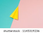 Yellow paper airplane on pastel pink and blue background. Minimal flat lay school concept.