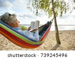 happy elderly woman enjoying in hammock at the beach, sunny autumn day