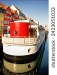 Small photo of Picturesque view in Copenhagen, with a 1919 ferry ship replica in red, white and black colors, and colorful old downtown apartment buildings at the background.