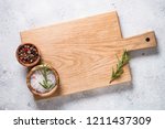 Wooden cutting board with sea salt and pepper on white stone table. Top view copy space.