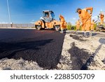 Small photo of Zrenjanin, Vojvodina, Serbia - June 8, 2021: Workers are using rakes to level, set up layer of fresh tarmac to right measures, steamroller is flatting fresh asphalt .