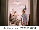 Small photo of Two teenage pretty girls showing their clothes to eachother in the shop