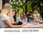 Small photo of Happy students discussing college subject before exam while sitting at table outdoors