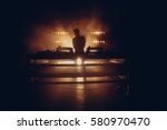 DJ set on a stage, silhouette in a warm backlight with two turntables