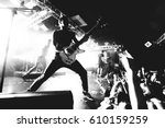 Guitarist on a stage playing rock to the crowd of people. black and white
