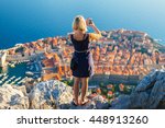 Female traveller make a panoramic photo of the old city of Dubrovnik from the mountain to her phone for Instagram or other social networks. Travel to Croatia. Summer vacation.