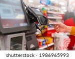 close up human female hand 
 with pos cashier machine Retail, credit card payment service. Customer paying for order of cheese in grocery supermarket store shop.