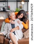 Small photo of happiness asian family candid of daughter hug grandparent mother senior elder mom cozy relax on sofa couch in living room,Beautiful family of mother and daughter together, hugging and kissing at home