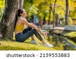 Small photo of relax casual asian female sportwoman break time after finish morning run exercise healthy lifestyle ,asian female relax cooling down after run training under the tree near water in the park