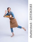 Small photo of young asian waitress barista wearing apron hand hold bread and coffee drink on wooden tray smiling warm welcome invite customer to her coffee shop studio shot on white background