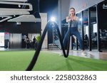 Small photo of Battle ropes session. Attractive young asian woman begin newbie working out in functional training gym doing crossfit exercise with battle ropes copyspace battling ropes cross-fit workout motivation