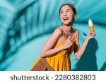 enjoy smiling attractive asia teen female woman wear casual yellow cloth happiness facial expression hand hold ice cream waffle cone summer lifestyle vacation travel studio shot on blue colour 