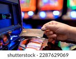 Small photo of Slot Machine gambling bet Play Time. Female Gambler Hand hold credit card ready to win the game with one best shot casino close up female Hand holding credit card playing slot machine gambling closeup
