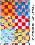 Small photo of Part of symmetric geometry pattern color patchwork quilt as background. Scrappy blanket with pattern of small squares. Handmade. Top view. Concept of hobby.