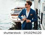 Young handsome man in classic suit over the blurred lake buttoning his jacket